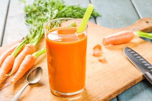 A glass of carrot juice with fresh carrots