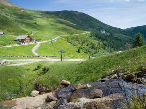 landscape view of the ski region meran 2000 with mountain inn in the background and green meadows and hiking trails,as well as a water source in the foreground in the summer of 2014