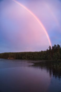 Rainbow reflected in the lake when it rains. in the background forest, on the lake reeds and water lilies. Nature photos from Sweden