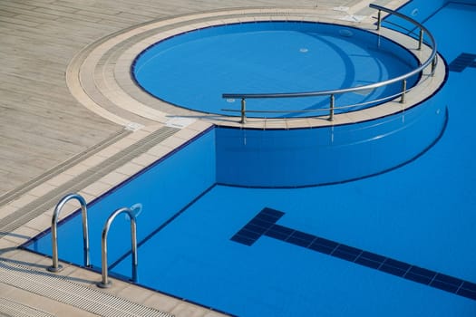 top view closeup detail of outdoor pool with blue water and entrance with chrome grab bars
