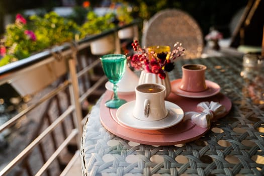 front view closeup of traditional Turkish coffee cups served outside with water flowers and delight dessert in romantic setup on glass table at sunset