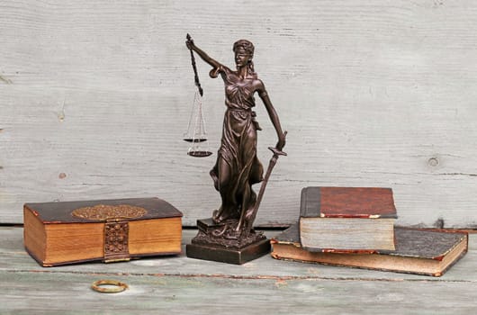 Justice figure and old books on a wooden background. Justice, scales and court