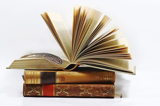 Three old books and a pen against a white background
