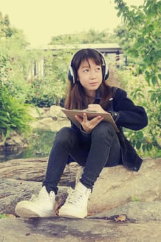 Young beautiful girl are drawing and listen to music in the park