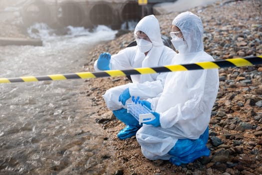 Scientist or Biologist in a protective suit and protect mask collects sample of waste water from industrial for analyze, problem environment, Ecologist sampling water from the river with test tube