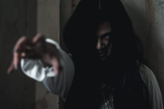 Scary ghost woman. Asian ghost or zombie horror creepy scary have hair covering face and eye reach arm out at abandoned house dark room, female makeup terror zombie face, Happy Halloween day concept