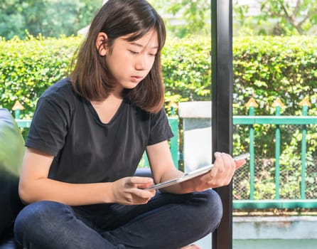Young girl studying online from digital tablet on the sofai n living room at home