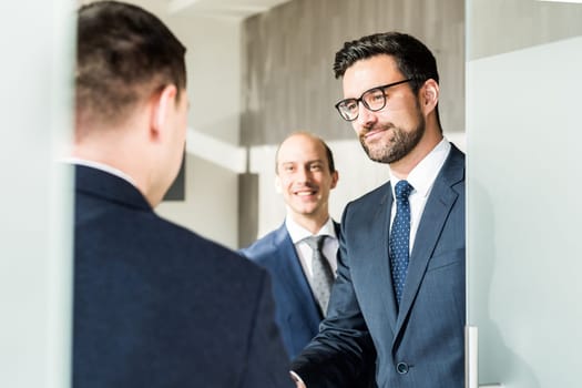 Group of confident business people greeting with a handshake at business meeting in modern office. Closing the deal agreement by shaking hands. Business and entrepreneurship success concept.