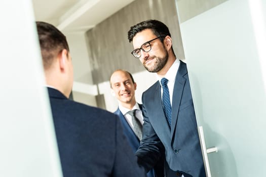 Group of confident business people greeting with a handshake at business meeting in modern office. Closing the deal agreement by shaking hands. Business and entrepreneurship success concept.