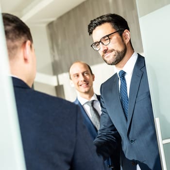 Group of confident business people greeting with a handshake at business meeting in modern office. Closing the deal agreement by shaking hands. Business and entrepreneurship success concept.