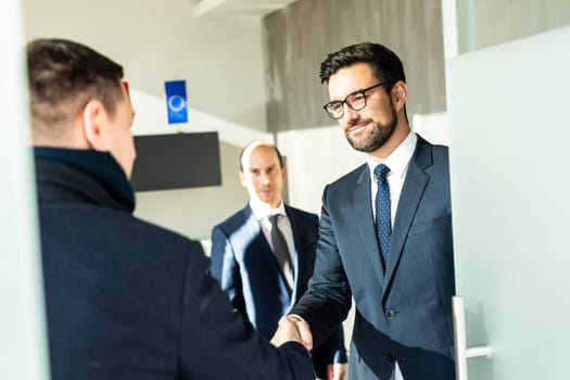 Group of confident business people greeting with a handshake at business meeting in modern office. Closing the deal agreement by shaking hands. Business and entrepreneurship success concept.