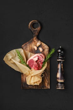 Raw fresh lamb double loin chop wrapped in paper on wooden cutting board