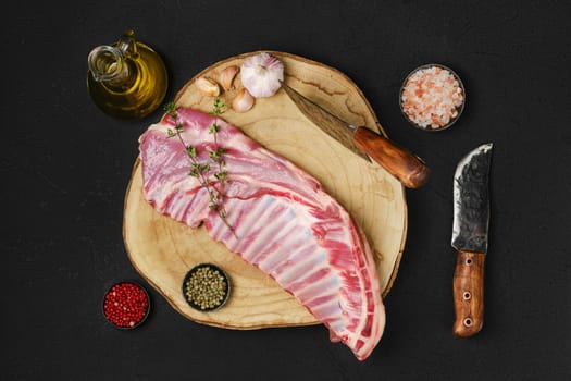 Top view of raw fresh lamb ribs, uncut with spices and herbs on wooden block