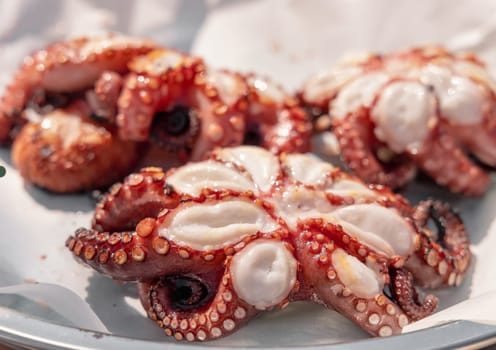 Freshly grilled octopused on a plate outdoor, Italy. Traditional Mediterranean cuisine. Eating seafood outdoor during summer time. Rustic style grilled octopuses bbq