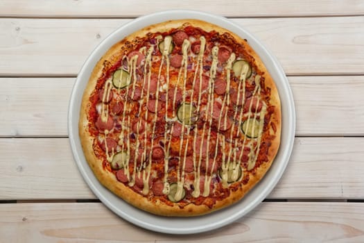 Top view of pizza with thin sausage and pickled cucumber