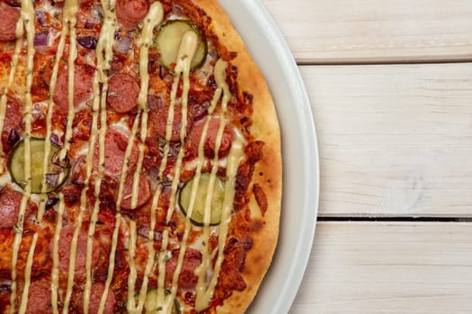 Top view of pizza with thin sausage and pickled cucumber