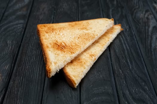Two pieces of toast bread on dark wooden table. Top view.