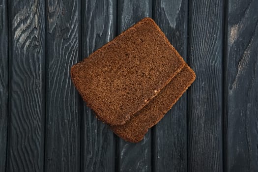 Two pieces of brown bread on dark wooden table. Top view.