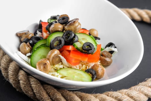 Closeup plate with salad with mushroom, olives, cucumber and pepper. Closeup view.