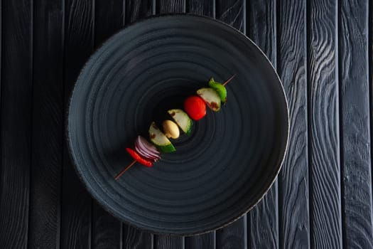 Top view of grilled zucchini, bell pepper, mushroom, tomato and onion on skewer