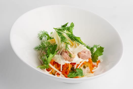 Plate with tuna salad with eggs, carrot, onion and mayonnaise on white background