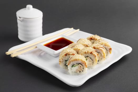 chicken teriyaki roll with chopsticks and soy sauce on a plate