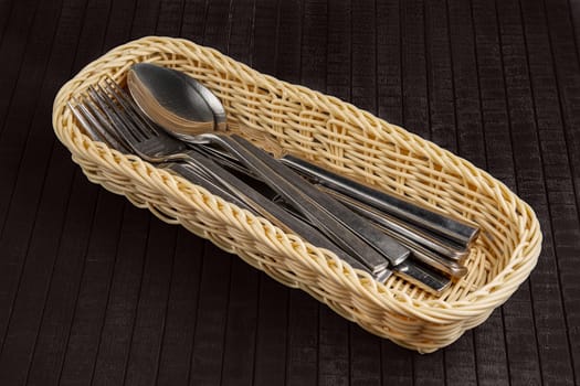 Wicker basket for knives, forks and spoons. Braided pottle with stainless steel utensil.