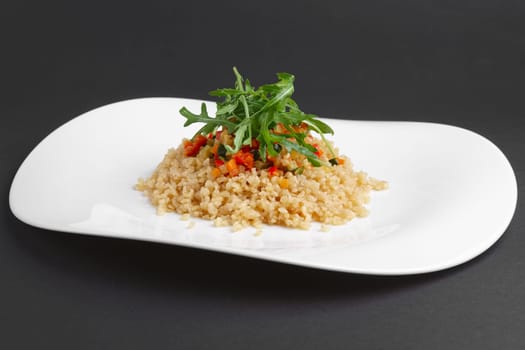 Traditional russian lenten salad with pearl barley, tomato, marrow squash, corn, zucchini and paprika.