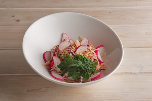 Portion of salad with radish, carrot and apple on a plate
