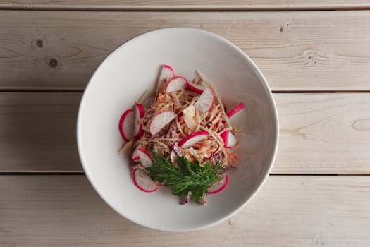 Portion of salad with radish, carrot and apple on a plate