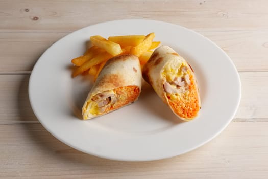 Meat, spicy carrot, cabbage and cheese rolled up in thin pitta bread on a plate