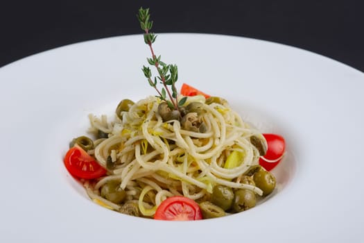 Traditional lenten spaghetti with shallot, tomato, rosemary and olives on a plate