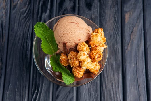 A cup of chocolate ice cream decorated with caramel popcorn and mint leaves. Top view.