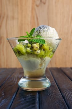 A cup of apple ice cream decorated with kiwi, mint leaves and poppy
