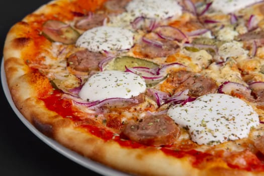 Closeup photo of pizza with sausage, pickled cucumber, onion and horseradish. Selective focus.