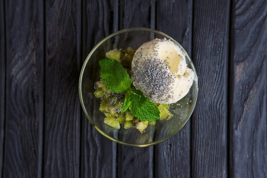 Top view of apple ice cream decorated with kiwi, mint leaves and poppy