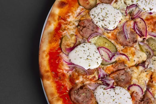 Top view of pizza with sausage, pickled cucumber, onion and horseradish