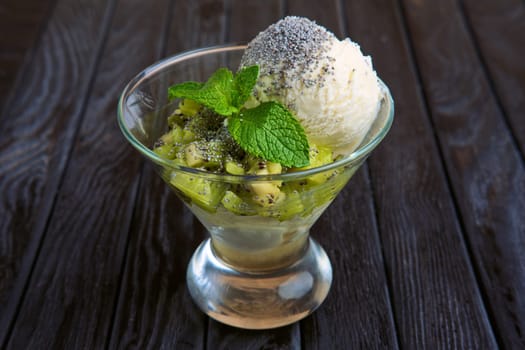 A cup of apple ice cream decorated with kiwi, mint leaves and poppy