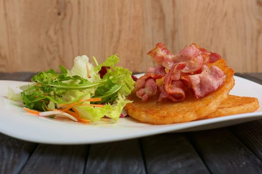 Traditional russian draniki with bacon and salad. Low angle view.