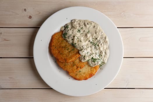Traditional belorussian potato pancakes draniki with mushroom sauce on a plate