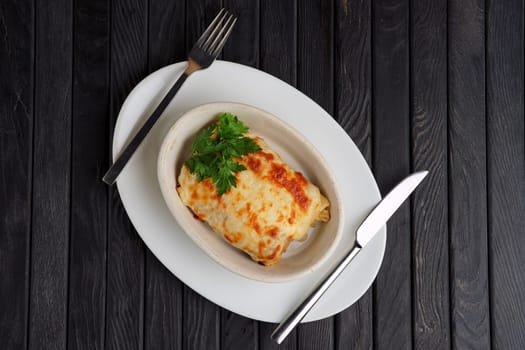 Top view of deep plate with pancakes covered with melted cheese.