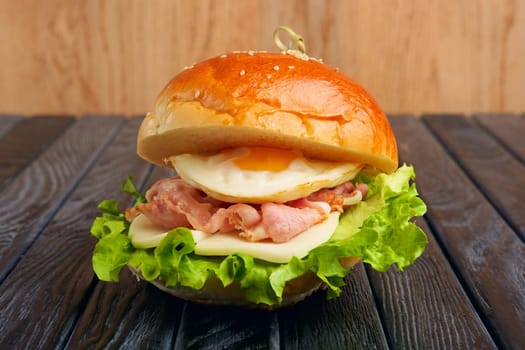 Tasty Egg burger with mozzarella, salad, and fried bacon