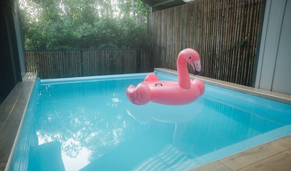 Pink inflatable ring flamingo plastic in the swimming pool blue water, Pool accessory equipment float for party, Trendy summer vacation feeling concept