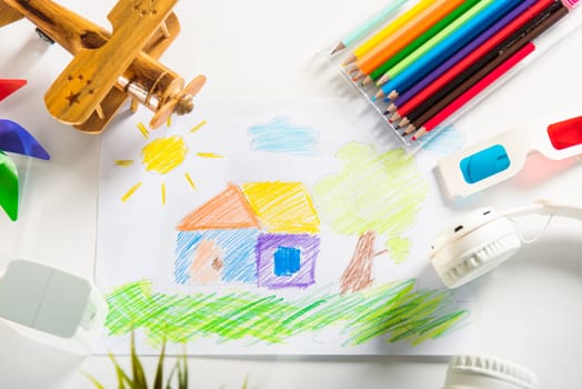 Child colorful drawing landscape my home dream on white paper, kid preschooler draw country house picture with pencil on table, arts homework concept