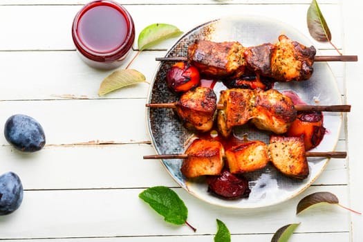 Fried meat on wooden skewers.Tasty kebabs in plum sauce