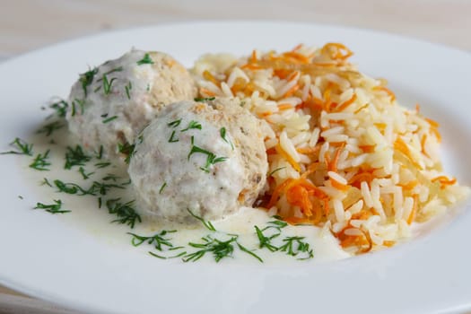 Close-up view of meatballs with rice and carrot.