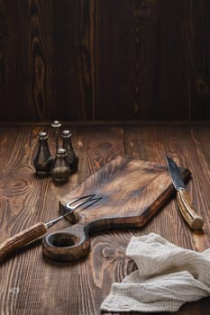Empty wooden cutting board, fork and knife with for steak on rustic wooden table