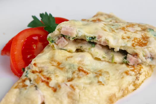 Closeup of omelet with ham and vegetables. Selective focus photo.