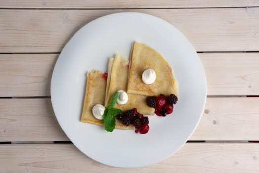 Portion on thin pancakes with sweet cream cheese and berries. Top view.