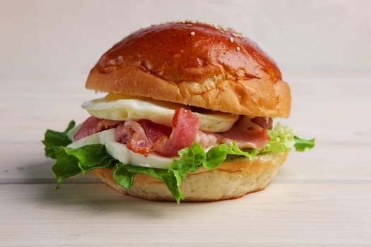 Soft focus photo of burger with mozzarella, bacon and fried egg.